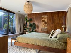 a bedroom with wood paneling and green bedspread in front of a large window