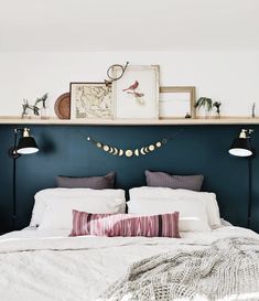 a bed with two lamps on either side of the headboard and one lamp above it