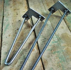 three pieces of metal sitting on top of a wooden table with screws in them