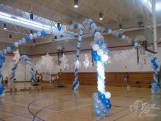 an indoor basketball court decorated with blue, white and silver balloons in the shape of snowflakes