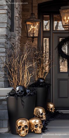 two large black pots with gold skulls in them on the front steps of a house