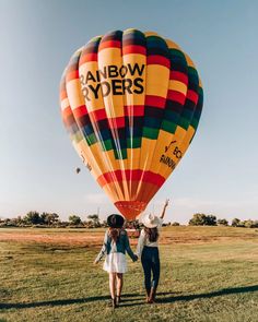 two women standing in front of a hot air balloon with the words rainbow dyers written on it