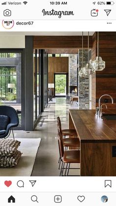 an open kitchen and living room with wood paneling on the walls, floor to ceiling windows