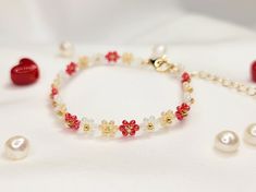 a red and white beaded bracelet with pearls, beads and other jewelry on a white surface