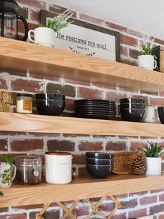 the shelves are filled with coffee cups and other items on display in front of a brick wall