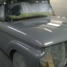 an old truck is being worked on in a garage with tarp covering the hood