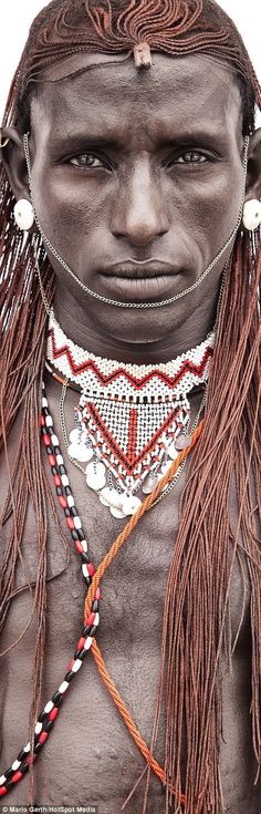 an image of a man with no shirt on wearing beads and necklaces in front of his face