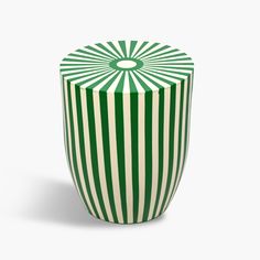 a green and white striped vase sitting on top of a table in front of a white background