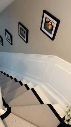 there are pictures hanging on the wall next to the stairs in this house with black and white checkered carpet