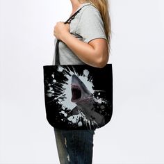 a woman holding a black and white shark tote bag