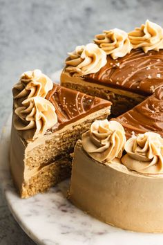 a cake with chocolate frosting on a marble platter next to a slice cut out