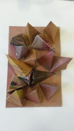 an origami sculpture is displayed on a white surface with brown and pink colors