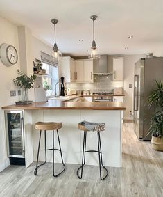 two stools are sitting at the bar in this modern kitchen with stainless steel appliances