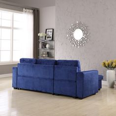 a blue couch sitting on top of a hard wood floor next to a vase filled with flowers