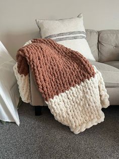 a couch with a blanket sitting on top of it next to a pillow and pillows