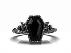 a black diamond ring is shown on a white surface with diamonds around the band and an oval shaped center stone