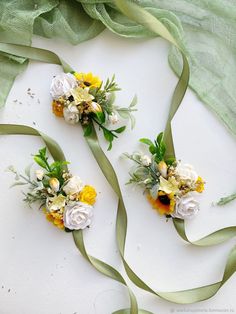 two bouquets of flowers with green ribbons on the floor next to eachother