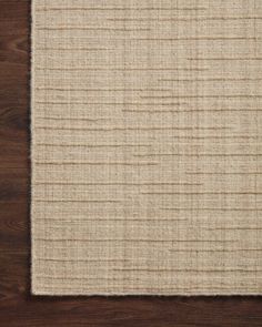 an area rug on top of a wooden floor next to a brown and white wall