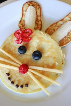 a plate topped with pancakes covered in fruit and veggies shaped like a mouse