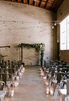 rows of chairs are lined up in an empty room with string lights and candles on the floor