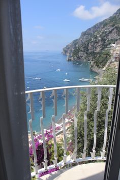 an open door leading to a balcony overlooking the ocean and boats in the water below