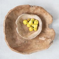 a wooden bowl filled with yellow fruit on top of a table