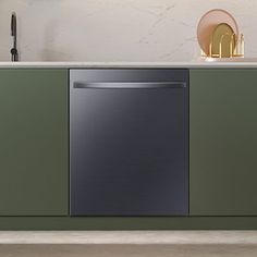 a kitchen with green cabinets and a black dishwasher on the counter next to it