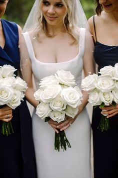 three bridesmaids holding bouquets of white roses