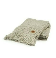 a grey blanket with fringes on it and a brown button in the middle,