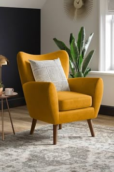 a yellow chair sitting on top of a wooden floor next to a potted plant