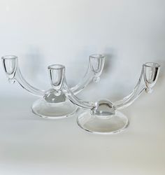 three clear glass candlesticks on a white background with one candle holder in the middle