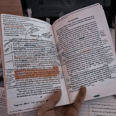 an open book with writing on it in front of a laptop computer and papers scattered around