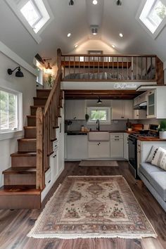 a living room and kitchen area in a tiny home with stairs leading up to the loft