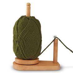 a green ball of yarn sitting on top of a wooden stand next to a knitting needle