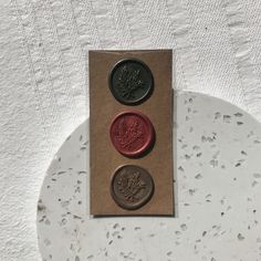 three waxed buttons sitting on top of a piece of paper