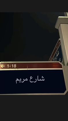 a street sign with arabic writing in front of a dark night sky and the moon behind it