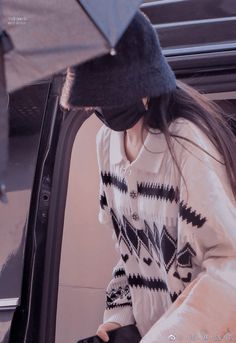 a woman with an umbrella sticking her head out the car window while wearing a hat