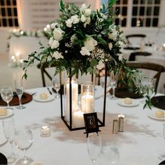 a centerpiece with candles and flowers on a white table cloth at a wedding reception