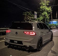 the rear end of a white car parked on the side of the road at night