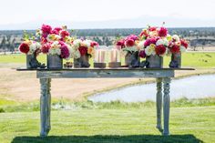 two vases with flowers are sitting on a table in the middle of a field