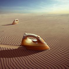 two irons sitting in the middle of a desert with sand dunes and blue sky