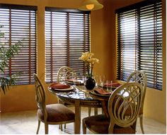 a dinning room table with chairs and plates on it in front of two windows