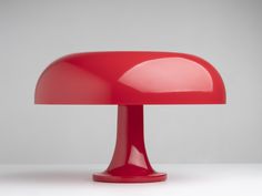 a red table lamp sitting on top of a white surface