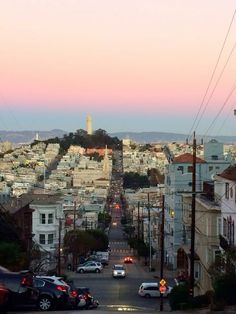 cars are parked on the street in front of a cityscape at sunset or dawn