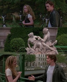 two people standing next to each other in front of a statue and another person talking on the phone