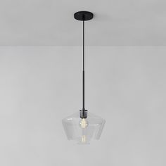 a clear glass light fixture hanging from the ceiling in a room with gray walls and flooring