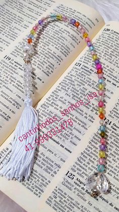 an open book with a tasseled beaded necklace on it's side