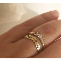 a woman's hand with two gold rings on top of her finger and the other ring