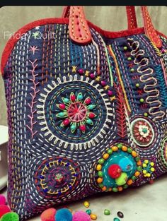 a colorful handbag sitting on top of a table next to pom poms