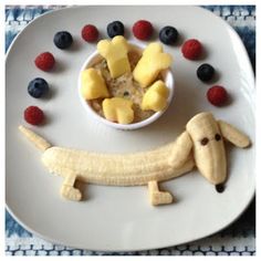 a white plate topped with fruit and a dog cut out in the shape of a banana